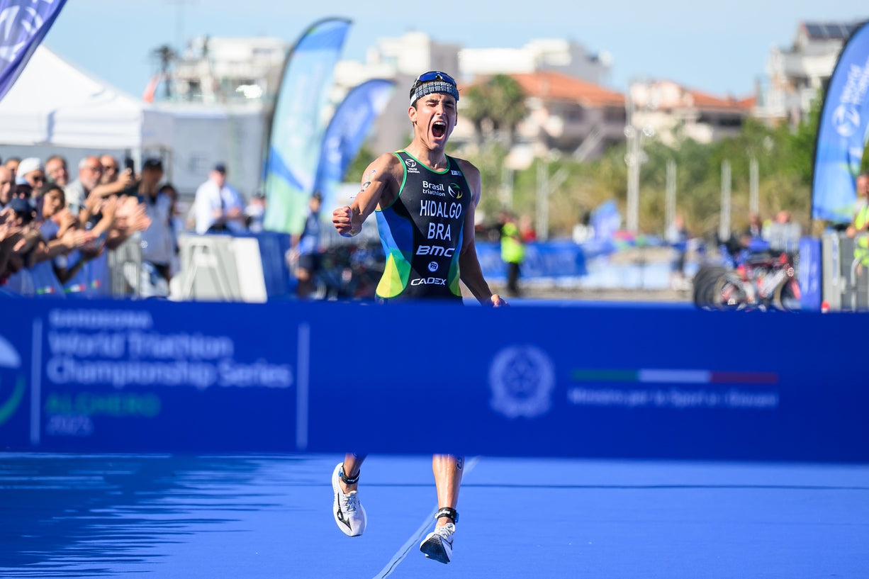 Athlete crossing the finish line at a triathlon event with 'BMC' branding.